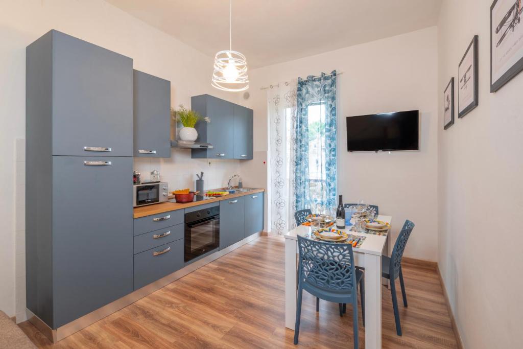 a kitchen with blue cabinets and a table with chairs at Piombino Apartments Casa Collodi II in Piombino