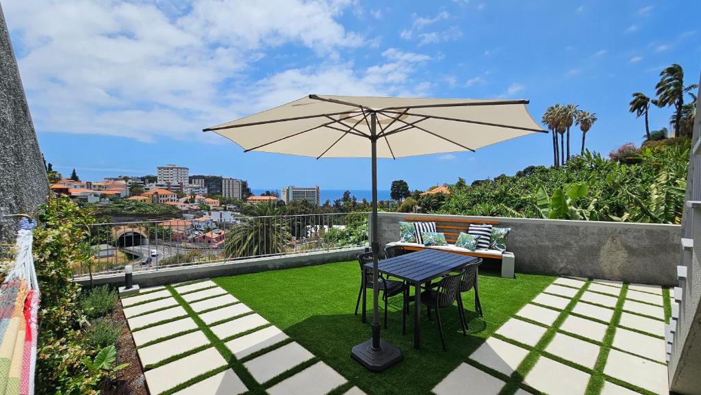 a patio with an umbrella and a table and chairs at Magnólia Residence in Funchal