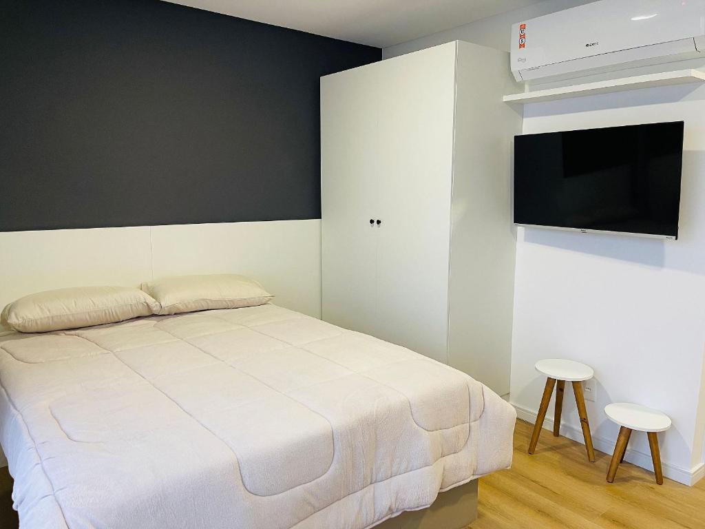 a bedroom with a bed and a flat screen tv at LOFT UP 1309 | Mobiliado | WIFI | Piscina | in Blumenau
