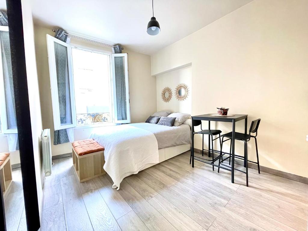 une chambre avec un lit, une table et des chaises dans l'établissement Studio neuf à 2 pas du métro, aux Lilas