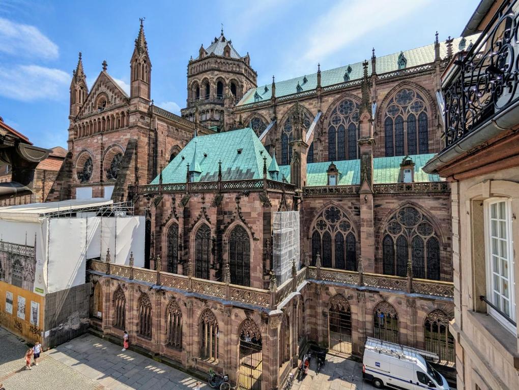une grande cathédrale en briques avec un toit vert dans l'établissement Triplex place de la cathédrale, à Strasbourg