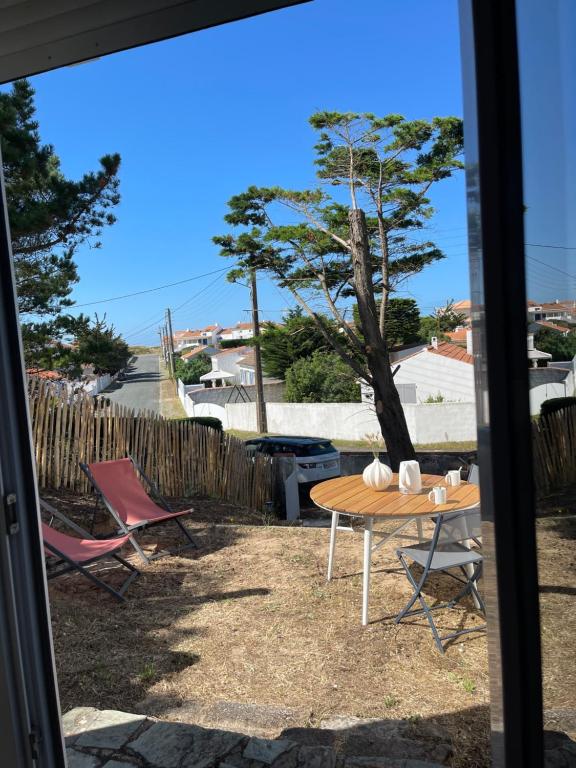 une table et des chaises dans une cour avec un arbre dans l'établissement L'aventurine NO, à Barbâtre