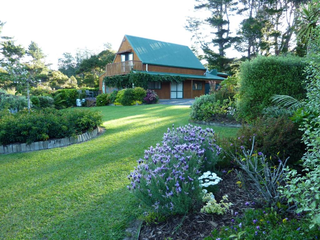 ein Haus mit einem Garten mit lila Blumen im Hof in der Unterkunft Waikare Cove in Russell