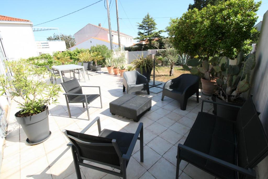 un patio avec des chaises, des tables et des plantes en pot dans l'établissement Agréable maison à pied de la plage et du centre avec wifi, à La Tranche-sur-Mer