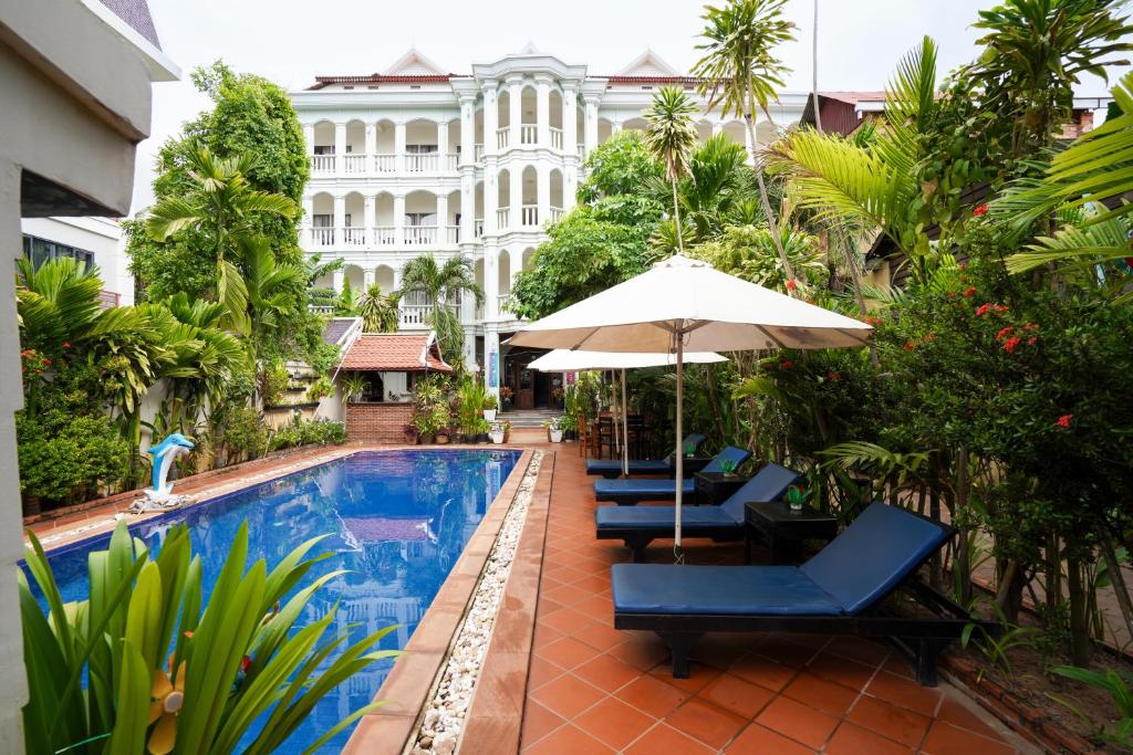 una piscina de hotel con sillas y sombrilla en Tan Sokchea Boutique, en Siem Reap