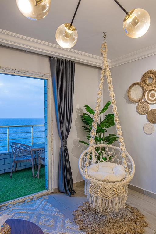 a swinging chair in a room with a view of the ocean at Skyline Premium Properties in Alexandria