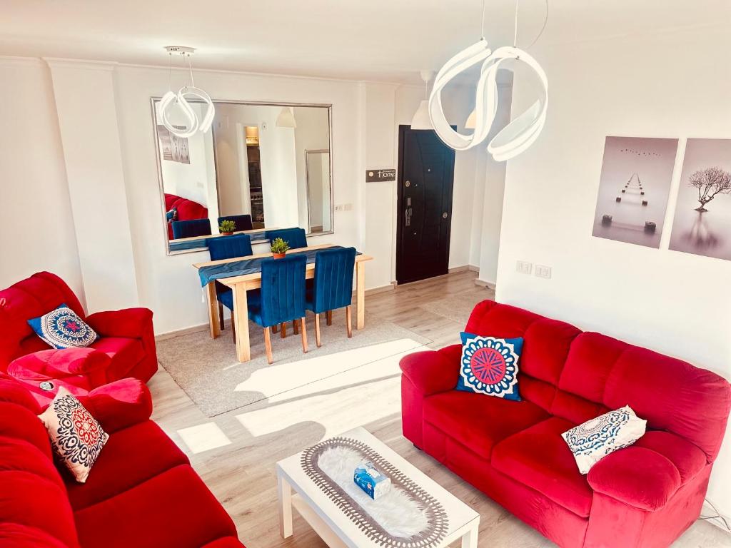 a living room with two red couches and a dining room at Madinaty Relaxation in Madinaty