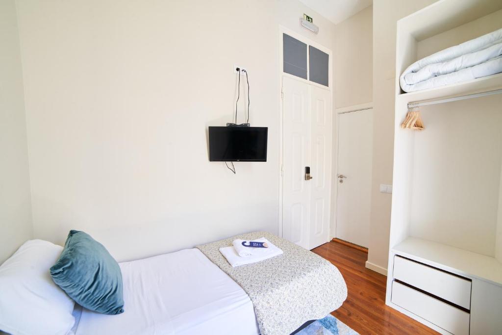 a bedroom with a white bed and a chair at Baron Faro - Guest House in Faro