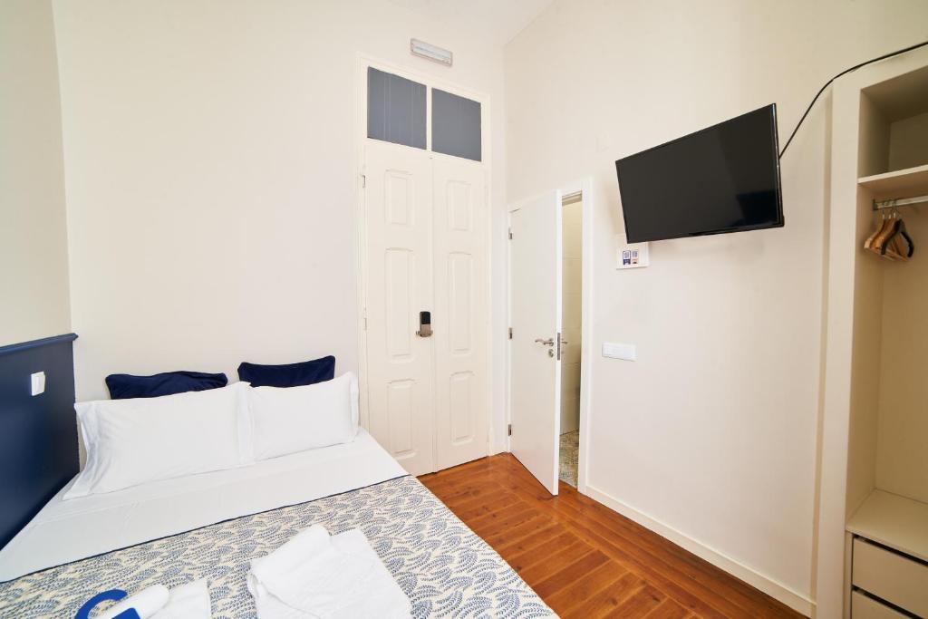 a bedroom with a white bed and a flat screen tv at Baron Faro - Guest House in Faro