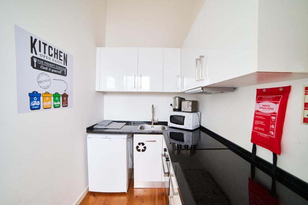 a small kitchen with white cabinets and a sink at Baron Faro - Guest House in Faro