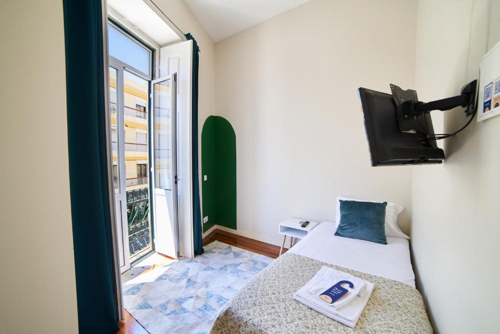 a bedroom with a bed and a tv and a window at Baron Faro - Guest House in Faro