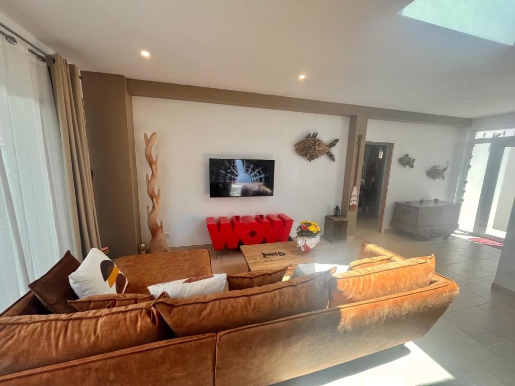- un salon avec un canapé brun et des fauteuils rouges dans l'établissement Villa Soleil, 300m de la plage, au Grau-dʼAgde