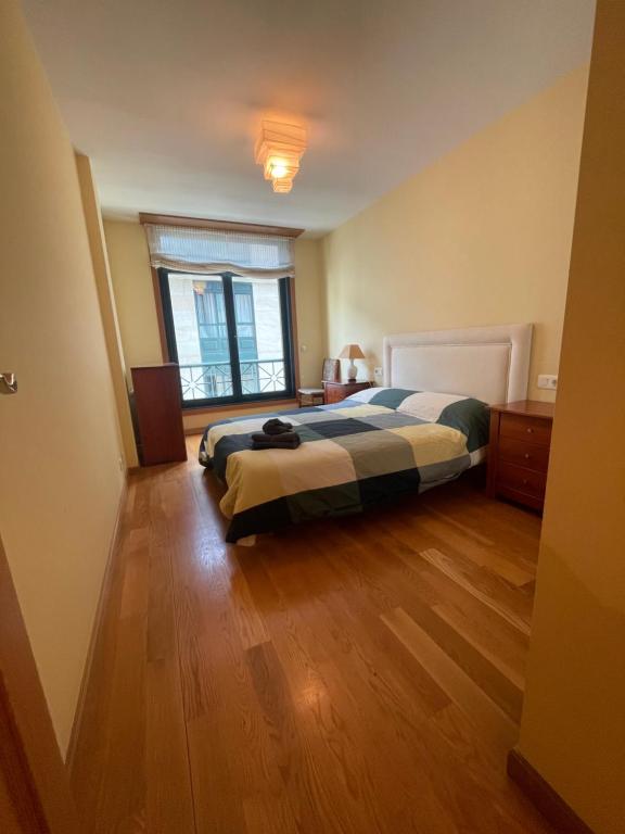 Un dormitorio con una cama y suelo de madera. en Apartamento en Ribeira a 200m de la playa, en Ribeira