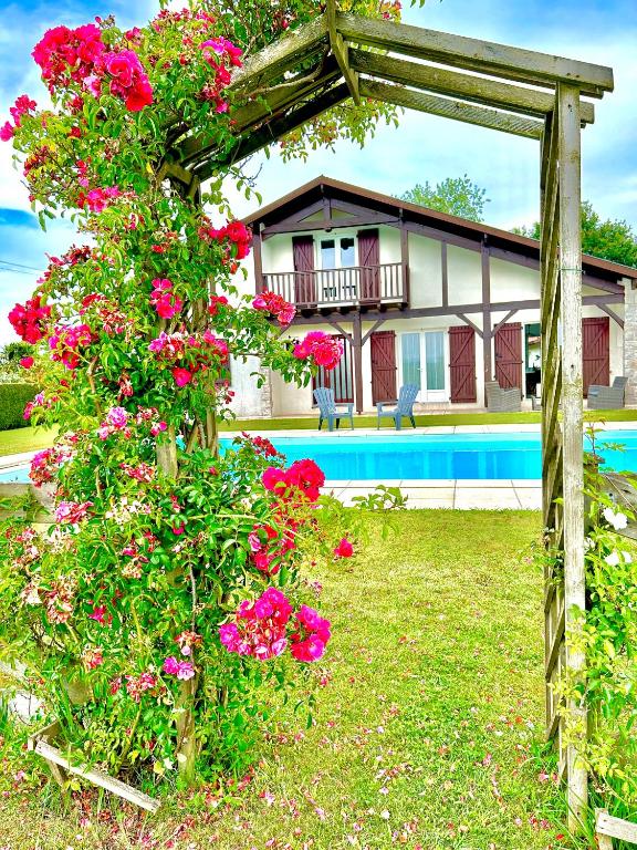 un jardin avec des fleurs roses en face d'une maison dans l'établissement La villa Landaise avec piscine, à Saubrigues
