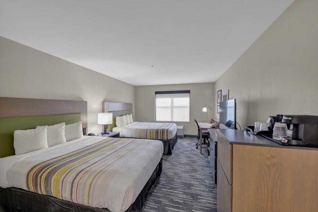 a hotel room with two beds and a desk at Country Inn & Suites by Radisson, Braselton, GA in Braselton