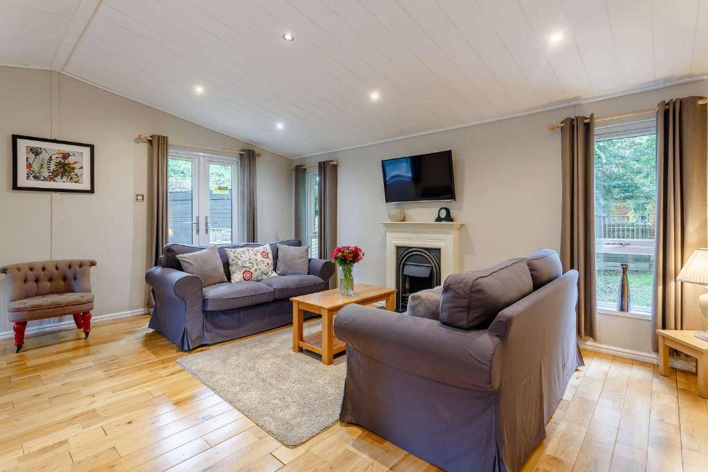 a living room with two couches and a fireplace at Blenheim Lodge 21 in Kingham