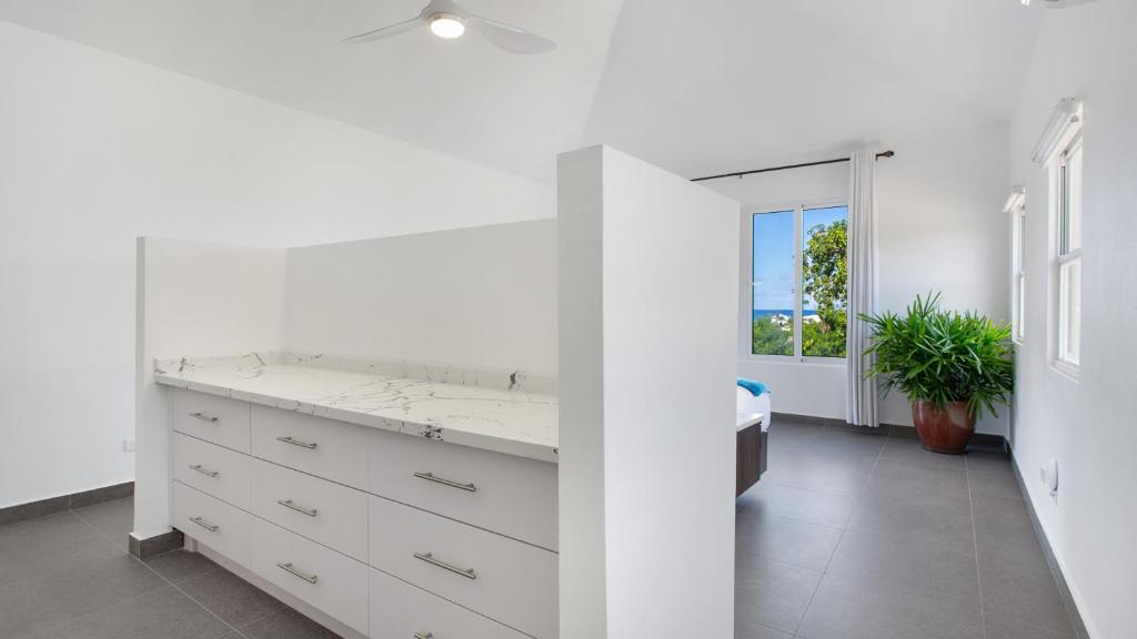 een witte badkamer met een wastafel en een spiegel bij Châlet Genesis in Meads Bay