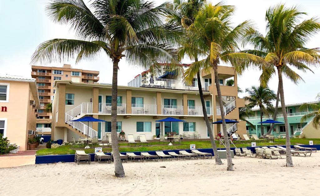 ein Hotel am Strand mit Stühlen und Palmen in der Unterkunft Enchanted Isle Hollywood Beach Resort in Hollywood