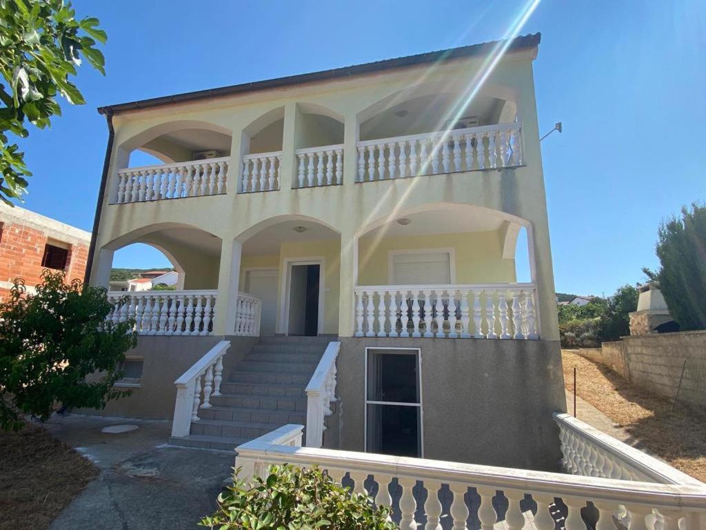 una grande casa bianca con scale e balcone di Apartmani Vlahek Stara Novalja a Stara Novalja