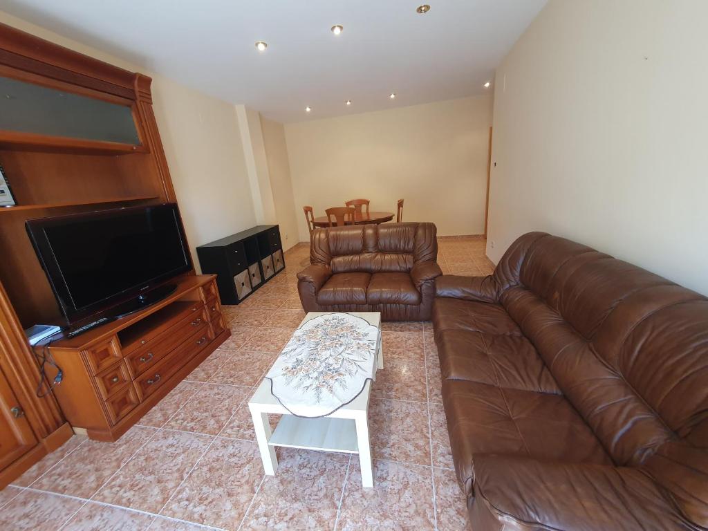 a living room with a leather couch and a tv at Apartamento para 8 personas en Alcalá de Xivert in Alcalá de Chivert