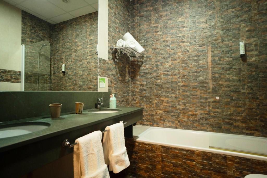 a bathroom with a bath tub and a sink and a bath tub at Hotel Albaida Nature in Mazagón