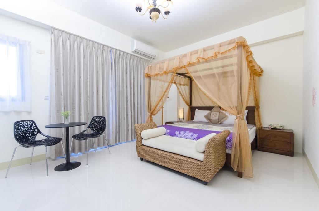 a bedroom with a canopy bed and a table and chairs at Happy House Homestay in Hualien City