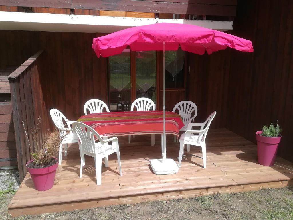 une table, des chaises et un parasol sur une terrasse dans l'établissement SAMOENS appartement proche du centre, à Samoëns
