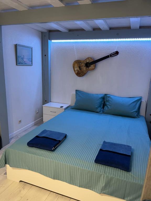 - une chambre avec un lit et une guitare sur le mur dans l'établissement Appartement en Rez-de-jardin, à Nice