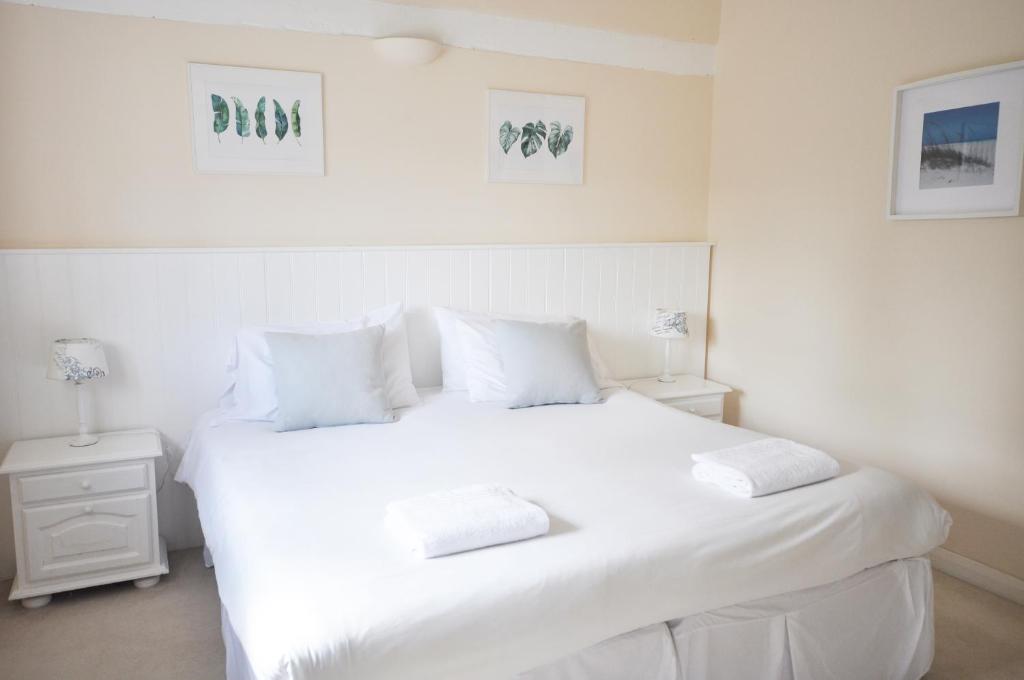a white bedroom with a large white bed with white pillows at Dairy Cottage in Shaftesbury