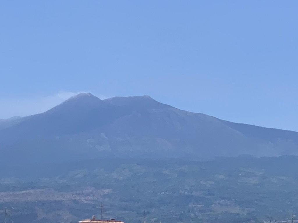 a mountain in the distance with a building in the foreground at Home Fiesta in Giardini Naxos