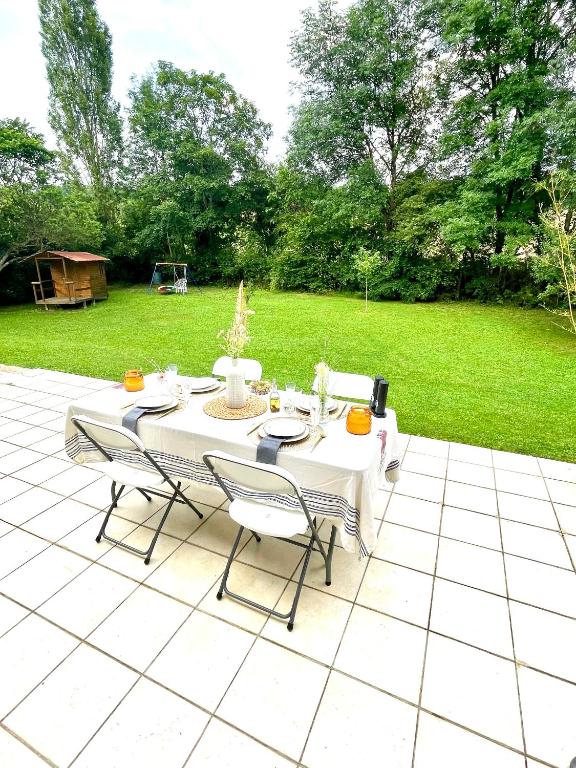 une table blanche et des chaises sur une terrasse dans l'établissement Chez Coccinelle, à Marmagne