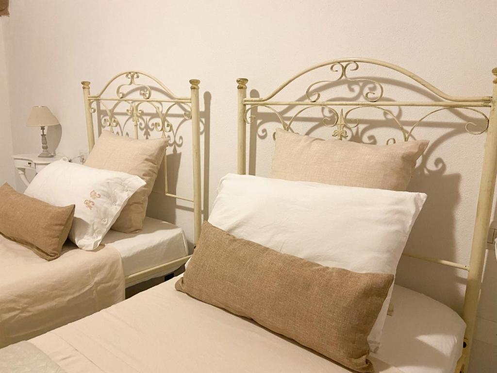 a bedroom with two beds with white pillows at CaTó - Le vacanze come a casa tua in Carloforte