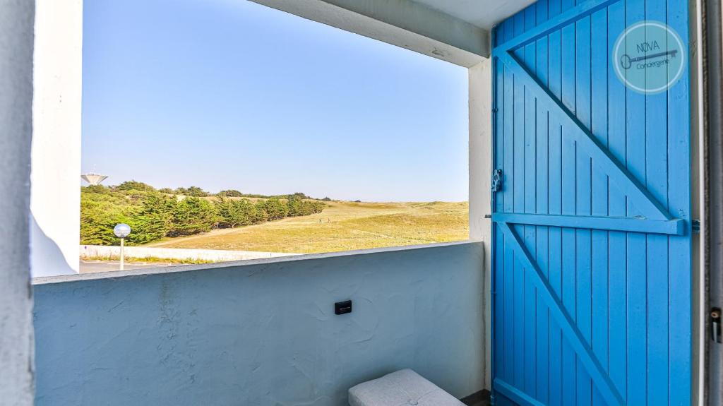 een blauwe deur met uitzicht op een veld bij La Goelette 30 in Saint-Hilaire-de-Riez