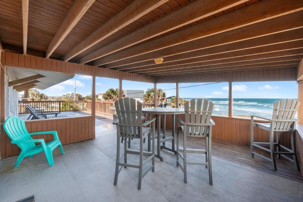 a porch with a table and chairs and the ocean at Beachside Bliss in Saint Augustine