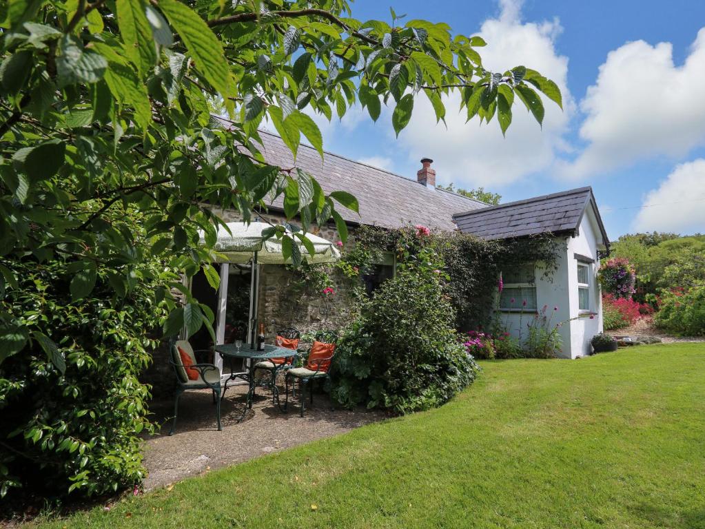 a cottage with a table and chairs in the yard at Trawsnant Cottage in New Quay