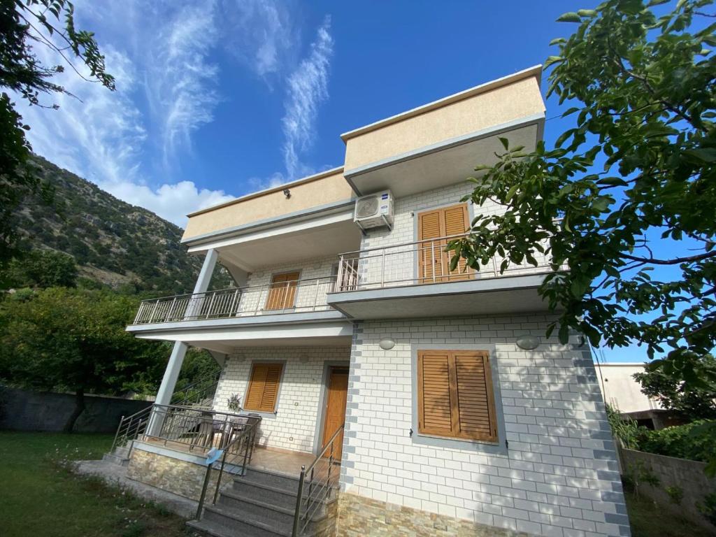 a white house with a balcony and stairs at Villa Pams in Baks-Rrjoll