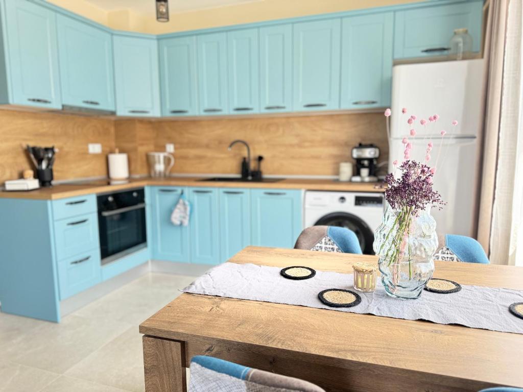 a kitchen with blue cabinets and a table with a vase of flowers at Boho and More in Sozopol
