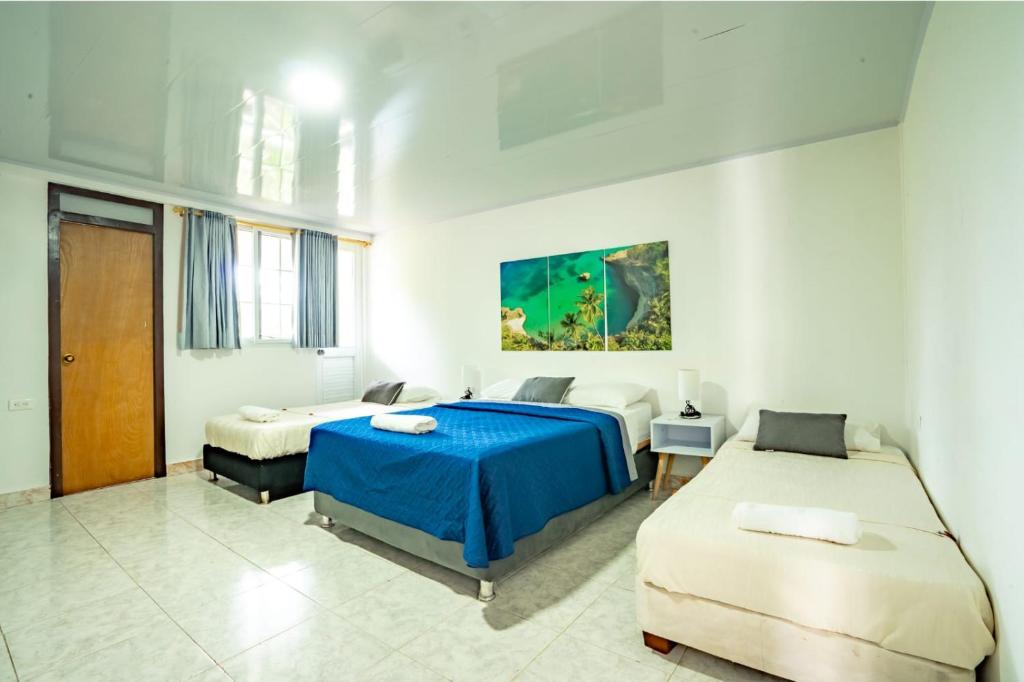 Un dormitorio blanco con dos camas y una manta azul. en Hotel El Pirata Morgan, en Providencia