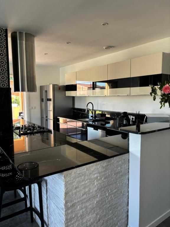 une cuisine avec des appareils en acier inoxydable et des comptoirs noirs dans l'établissement Maison tout confort à proximité des plages, à Villeneuve-Loubet