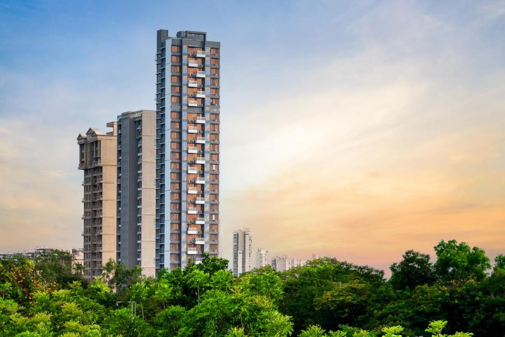 ein hohes Gebäude mit Bäumen davor in der Unterkunft Freesia Residency By Express Inn - Navi Mumbai in Navi Mumbai