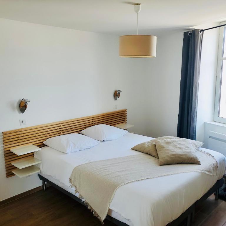 une chambre avec un lit blanc avec une tête de lit en bois dans l'établissement Les Halles 2, à La Rochelle