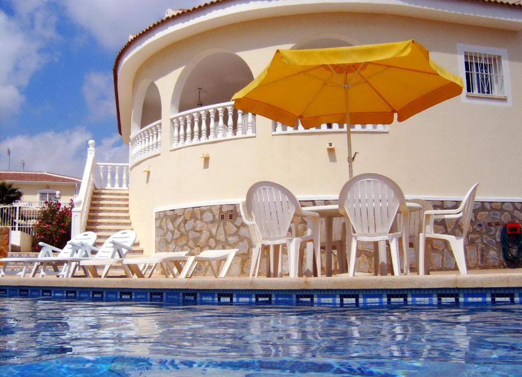 a group of chairs and an umbrella next to a swimming pool at Casa Sara - Private Villa with Private Pool in Ciudad Quesada