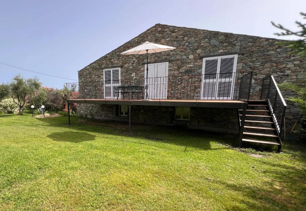 une maison avec une terrasse et un parasol dans l'établissement Maison enchanteresse à Santo-Pietro-di-Tenda avec jacuzzi, à Santo-Pietro-di-Tenda