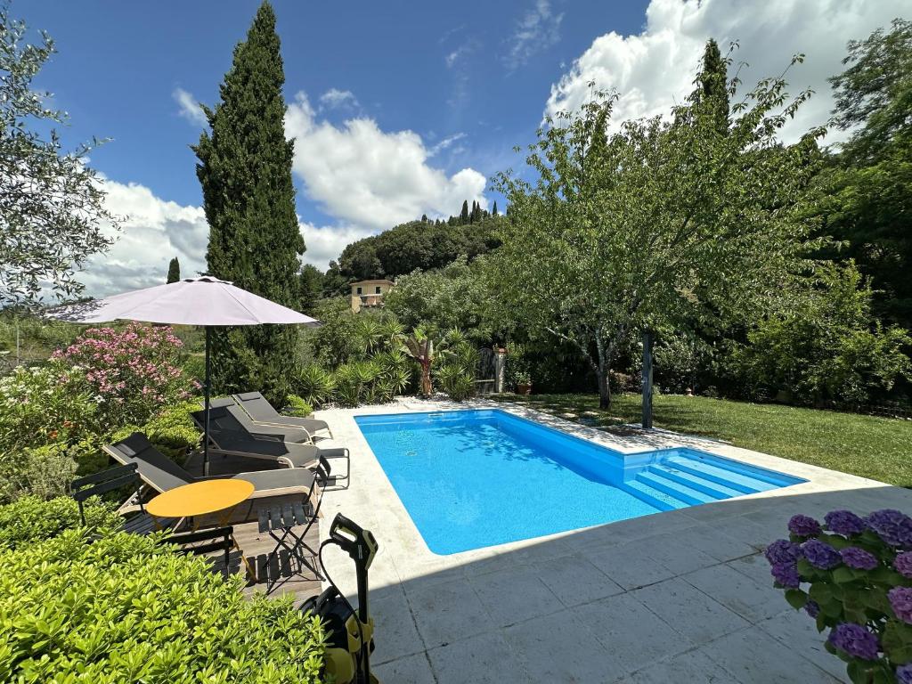 a swimming pool with a table and chairs and an umbrella at Villa Camilla 10 Pax by VILLASRETREATS in Sarzana