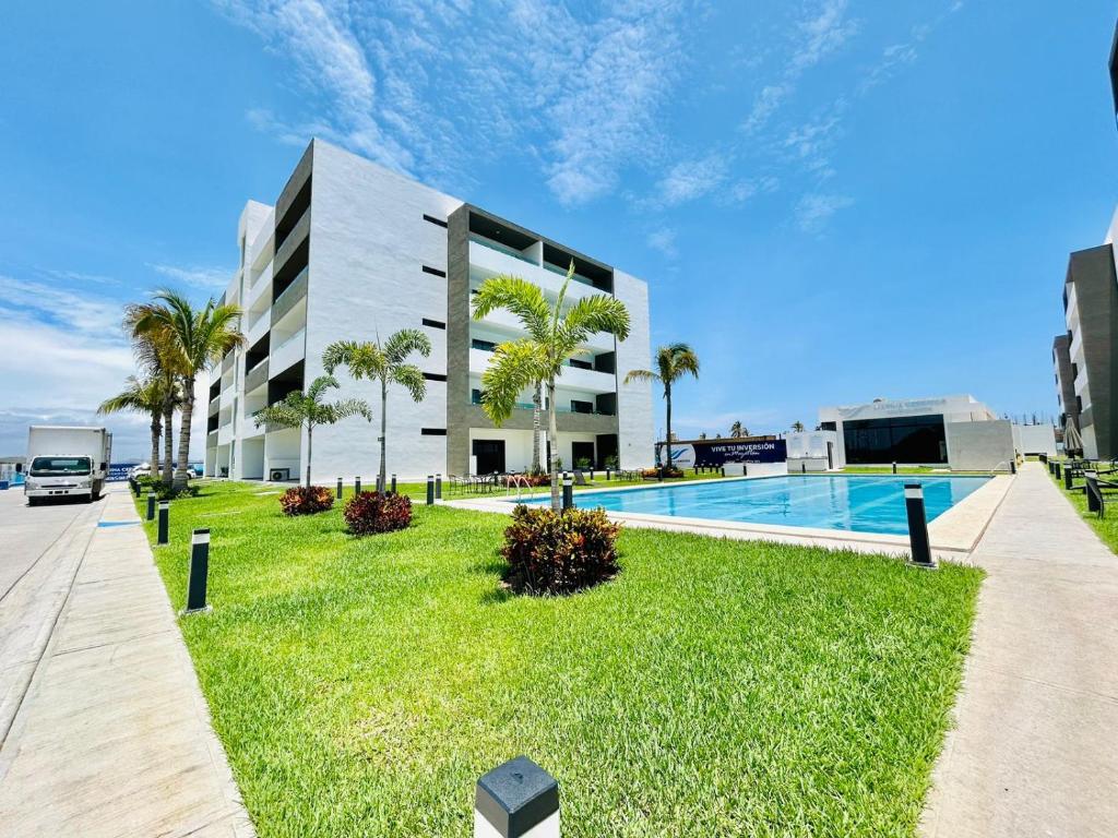 a large building with a swimming pool and palm trees at moderno con alberca cerca de la playa by G P S rentas in Mazatlán