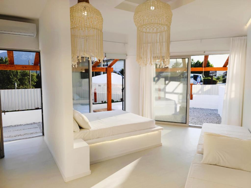 a white bedroom with two beds and chandeliers at Meteora Superior Collection Villas III in Kalabaka
