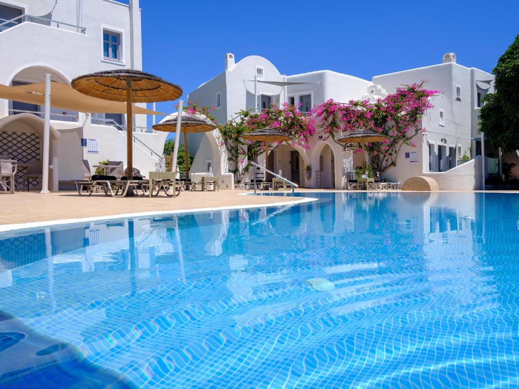 a swimming pool in front of a hotel with white buildings at Smaragdi in Perivolos