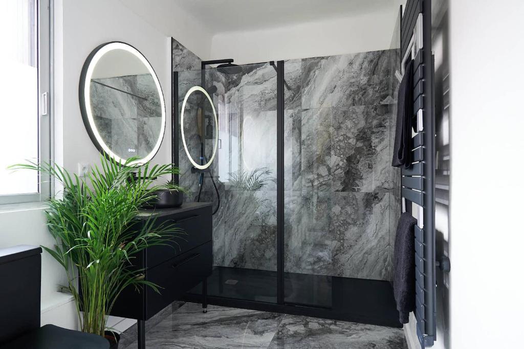 La salle de bains est pourvue d'une coiffeuse noire et d'un miroir rond. dans l'établissement L'Escale, à Marseille