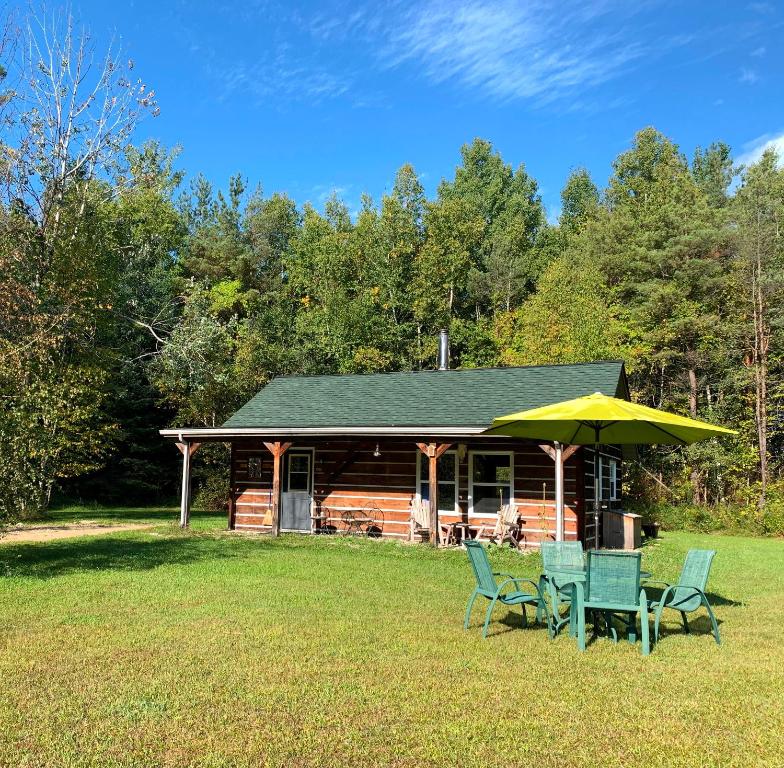 a log cabin with chairs and an umbrella at Nottawasaga Hideaway Bed and Breakfast in Collingwood