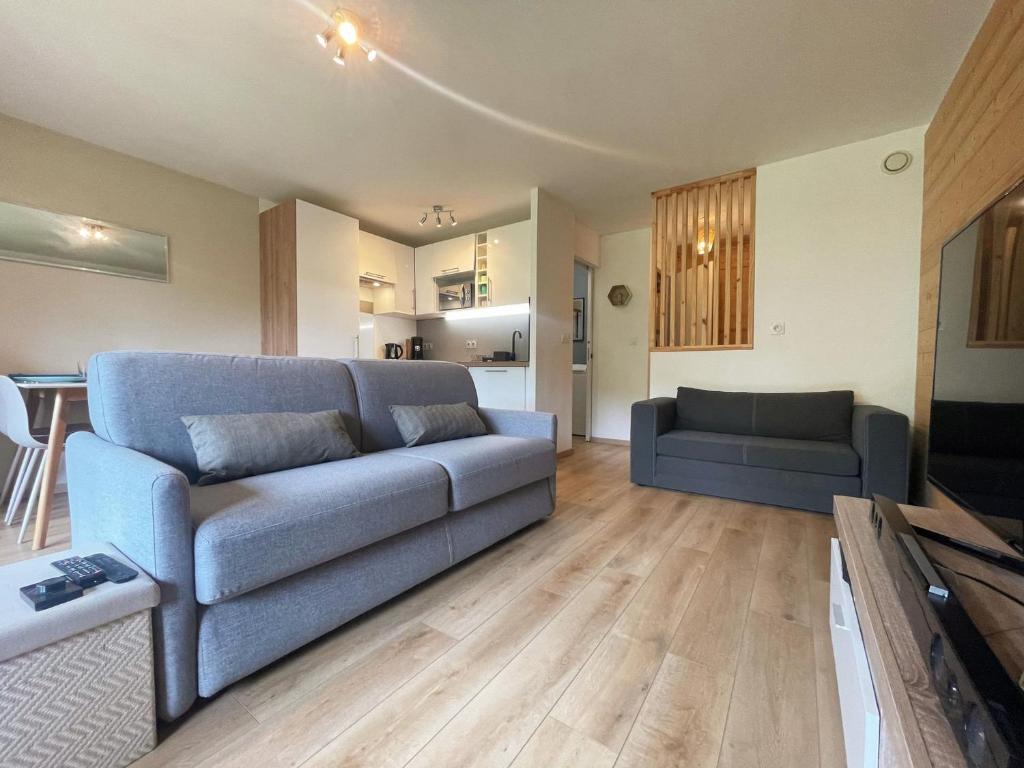 un salon avec un canapé bleu et une cuisine dans l'établissement Studio Cosy Proche Centre de Samoëns, Balcon, Parking & Proche Ski-Bus, Rénové avec Goût - FR-1-624-159, à Samoëns